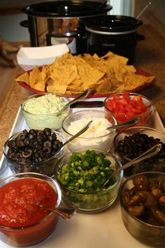 the food is ready to be eaten on the table for guests at this party, including tortilla chips and salsa