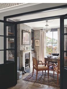 an open door leading to a living room with chairs and a fire place in it