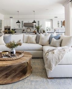 a living room filled with white furniture and lots of pillows on top of the couch