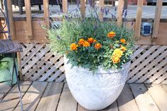 a planter filled with lots of flowers sitting on top of a wooden deck