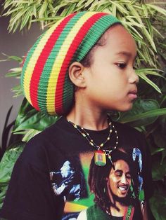 a young boy wearing a colorful hat and t - shirt with the image of bob marley on it