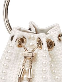 Find JIMMY CHOO Bon Bon Pearl-embellished Mini Bag on Editorialist. This Jimmy Choo Bon Bon mini bag is crafted from ivory satin with a pearl embellishment throughout. It features a logo engraved silver-tone hardware, metal tassel detail, chain-link shoulder strap, single metallic top handle, drawstring fastening, main compartment, and internal logo patch. Luxury Pouch Evening Bag With Pearl Handle, Luxury Evening Bag With Pearl Handle, Luxury Evening Bag With Handles For Events, Luxury Pouch Shoulder Bag With Pearl Handle, Luxury White Bags With Pearl Handle, Luxury Handheld Evening Bag With Pearl Handle, Luxury Embellished White Bags, Luxury White Embellished Bag, Luxury White Embellished Bags