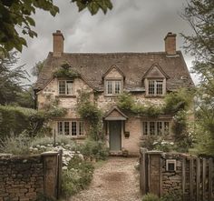 a stone house with ivy growing on it's roof and door, surrounded by greenery