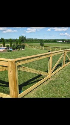 a wooden fence in the middle of a grassy field