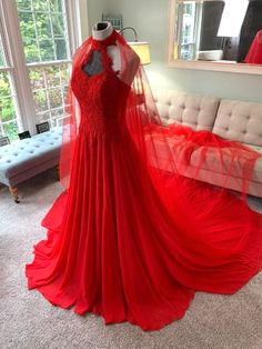 a red dress on display in front of a couch with a large mirror behind it