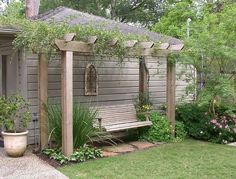 a wooden bench sitting in the middle of a garden next to a house and trees