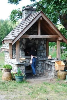 a woman standing in front of a stone oven