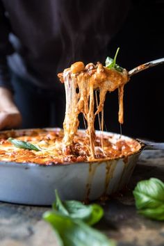 a person holding a fork with some food in it's mouth and lifting out the noodles