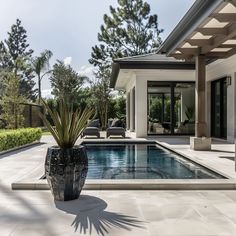 a large pool in the middle of a house with a patio and lounge area next to it