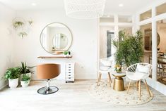 a living room filled with furniture and lots of plants on top of the table in front of a round mirror