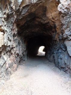 a tunnel in the side of a mountain with rocks on both sides and dirt floors