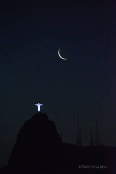 the crucifix is lit up in the night sky with a crescent above it