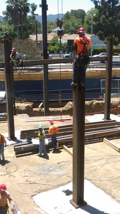 construction workers are working on the side of a train track as another man stands in the background