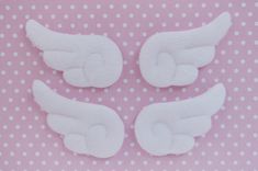 three white angel wings on a pink and white polka dot tablecloth with small dots