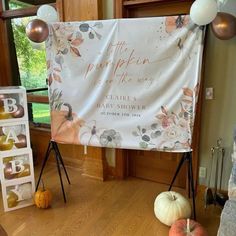 a large white banner sitting on top of a wooden floor next to pumpkins and balloons