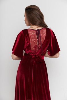 a woman wearing a red velvet dress with an open back and lace detailing on the shoulders