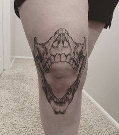 a woman's leg with a tattoo on it that has an image of a skull and teeth