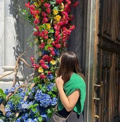 a woman standing in front of a door with flowers on it