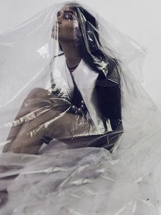 a woman sitting on the ground wrapped in plastic