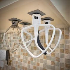 two kitchen mixers hanging from the ceiling in a room with tiled walls and flooring