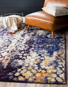 an area rug with a brown leather chair and pillow on the floor next to it