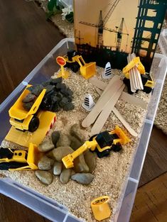 a plastic container filled with construction toys on top of a wooden floor next to a sign