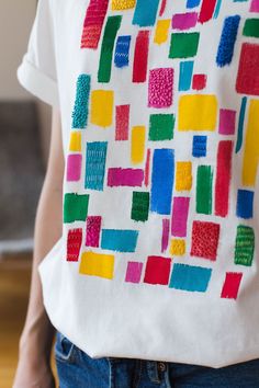 a person wearing a white t - shirt with colorful squares on it