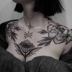 a woman's chest with flowers and stars tattooed on her upper part, in black ink