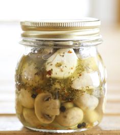 a glass jar filled with mushrooms on top of a wooden table