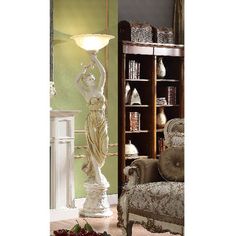 a white lamp sitting on top of a table next to a chair and bookshelf