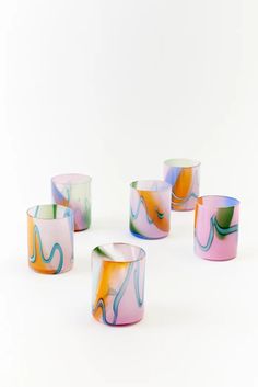 five different colored candles sitting next to each other on a white surface with one candle in the middle