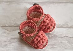 three crocheted baby shoes sitting on top of a white table next to each other