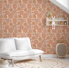 a white couch sitting in front of a wallpapered room with an orange flower pattern