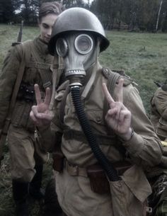 two men dressed in gas masks and holding up peace signs