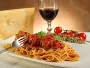 a plate of spaghetti with meatballs and parmesan cheese next to a glass of wine