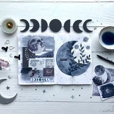 an open book with various items surrounding it on top of a white wooden table next to a cup of coffee