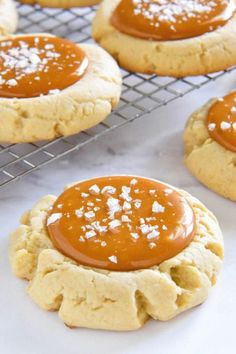 peanut butter cookies cooling on a wire rack with salt sprinkled on top and caramel sauce in the middle