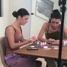 two women sitting at a table with nail polish