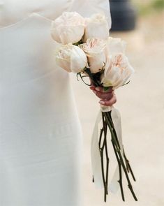 a bride holding a bouquet of white roses