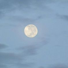 the full moon shines brightly in the sky above some clouds on a cloudy day