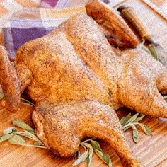 a whole chicken sitting on top of a wooden cutting board