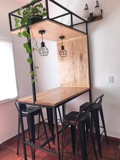 a table with stools and a plant in the corner on top of it, next to two black barstools