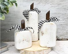 three white vases with black and white checkered bows are on a wooden stand