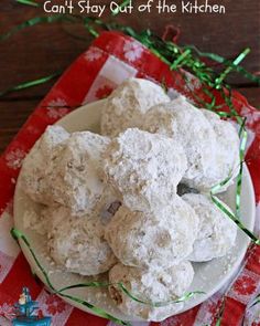 a white plate topped with snowball cookies on top of a red and white checkered cloth