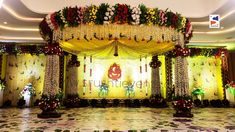 an elaborate stage set up for a wedding ceremony with flowers and greenery on the wall