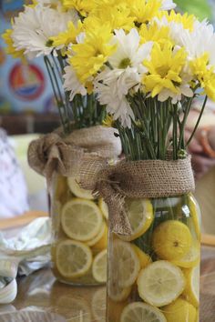 a jar filled with lemons and flowers on top of a table