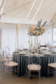 a table set up with white flowers and silver chairs