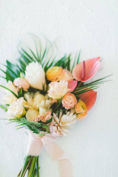 a bouquet of flowers on a white surface with green leaves and pink tulips