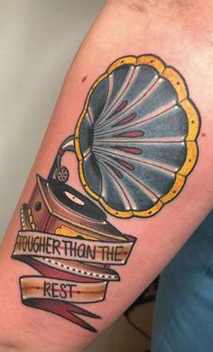 a tattoo on the arm of a person with a record player and ribbon around it