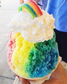 a rainbow ice cream sundae is in someone's hand